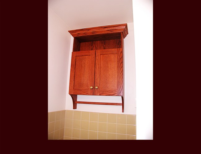 Oak Flat Panel Bath Cabinet with towel bar. Dyed finish. Crown Moulding. Over toilet storage.