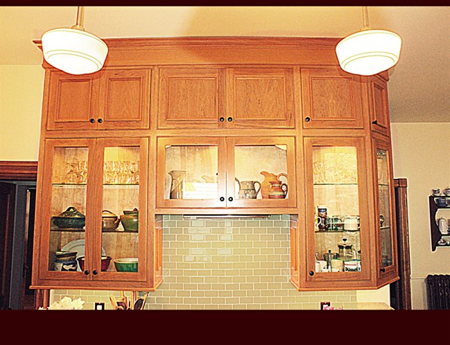 Custom Cherry Cabinets. Glass door cabinets with glass shelving and interior lighting. Light rail throughout.